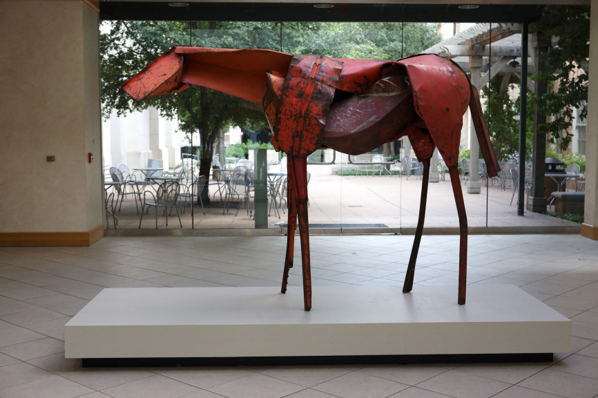 A red horse sculpture in front of a large window