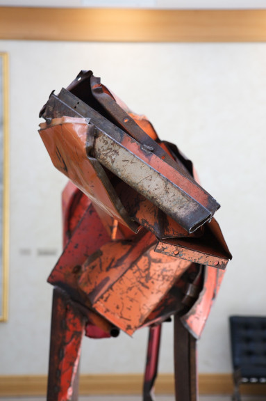 The head of a red horse sculpture in front of a large window