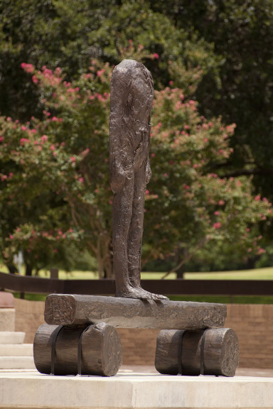 Headless statue in front of some vibrant plants