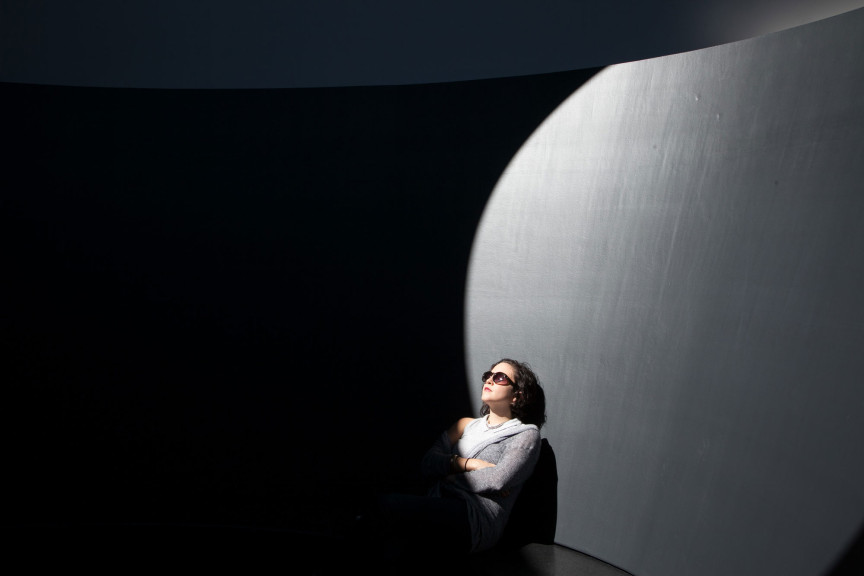 A woman inside a dark structure with light coming in