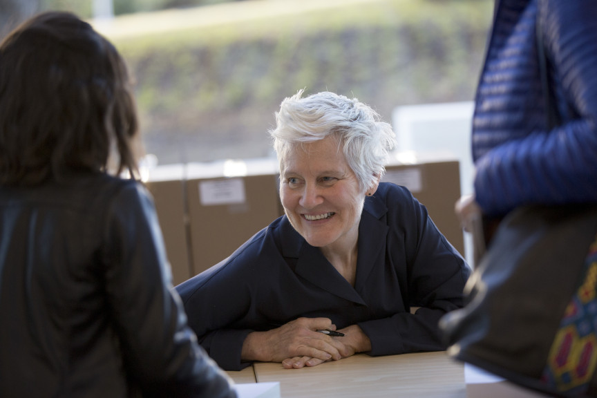 a person leaning down on table and looking at two people