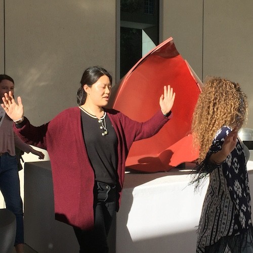 students dancing around red sculpture