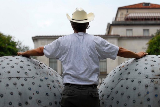 Image of cowboy standing next to Donald Lipski's "The West"