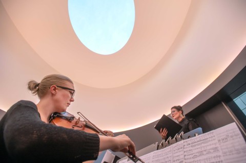 Two musicians perform under the oculus of James Turrell's "The Color Inside"