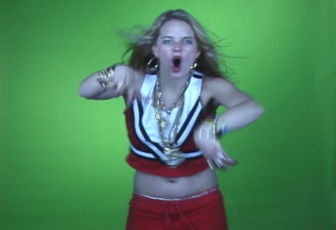 A woman dancing in front of a green wall.